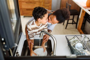 Imagem ilustrativa com uma mãe e uma filho lavando a louça juntos