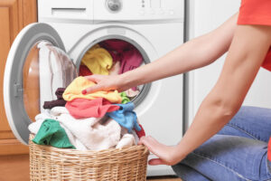 Ilustração com uma máquina de lavar e cesto com roupas coloridas