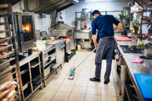 Ilustração de homem limpando a cozinha de um restaurante com um mop e cleaner desinfetante