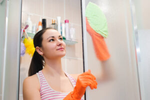Ilustração de mulher limpando o box do banheiro com pano alta performance